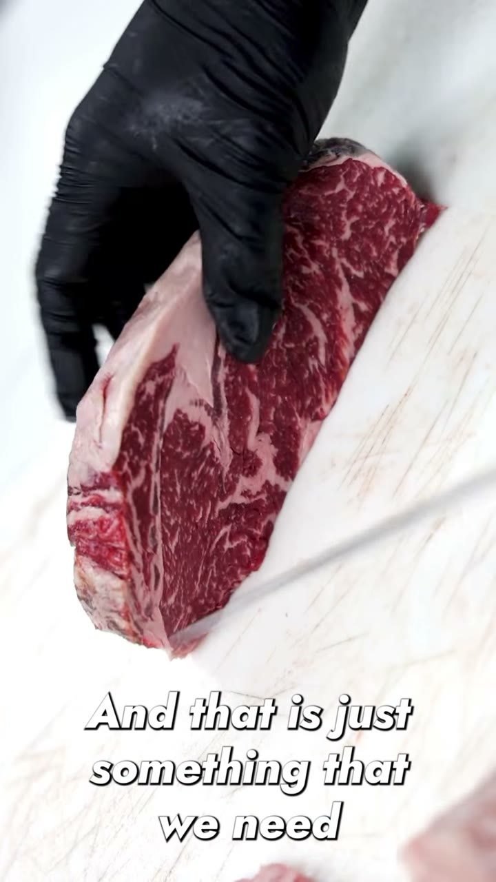 Gloved hand holding a heavily marbled ribeye